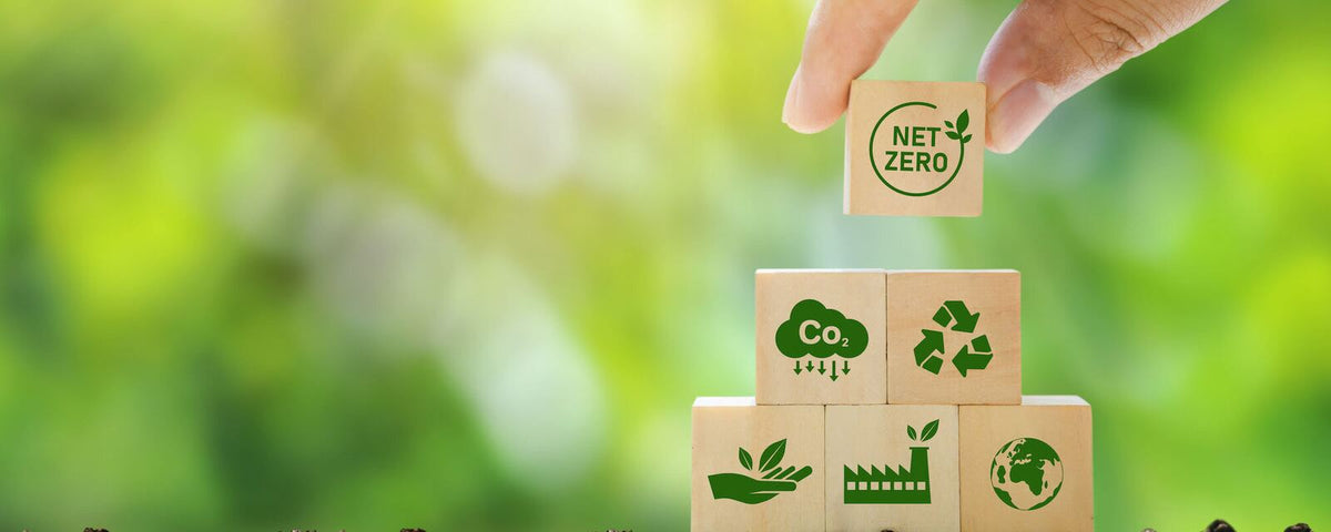 Hand stacking Net Zero, CO2, recycling and renewable energy blocks on soil