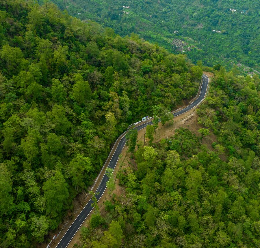Aerial view of a hill forest with a winding mountain road