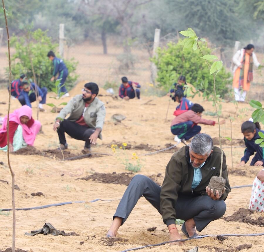 Villagers and volunteers planting saplings at a CSR tree plantation drive